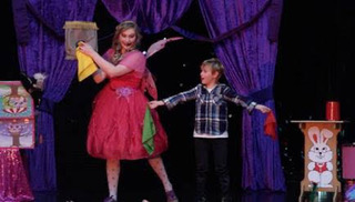 Fairy La La on stage doing magic with a young volunteer